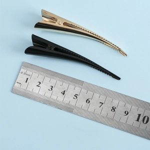 Detailed size comparison of gold and black metal hair clips showing 10cm length on ruler