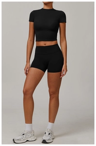 Detail view of black high-waisted yoga shorts and cropped short sleeve compression top