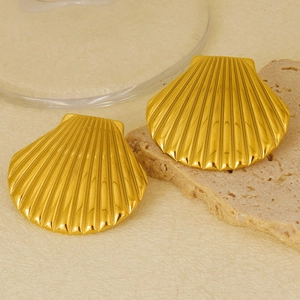 Detailed view of 18k gold plated stainless steel seashell earrings on a textured stone