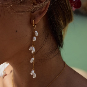Close-up of golden pearl tassel earrings worn by a model showcasing elegant drape and luster