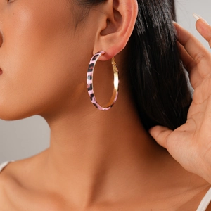 Pink leopard print hoop earring with gold inner circle shown on a female model's ear