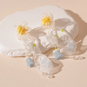Close-up of lace flower earrings with blue bead tassels and delicate organza fabric