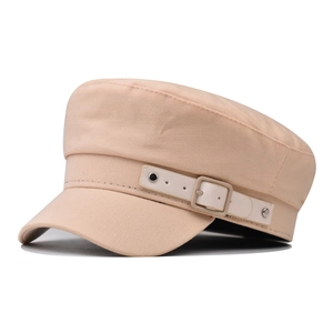Detail of beige cotton military cap featuring decorative leather buckle and silver rivets