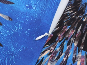 Macro dettagliata di una cerniera invisibile sul tessuto blu con stampa a piume
