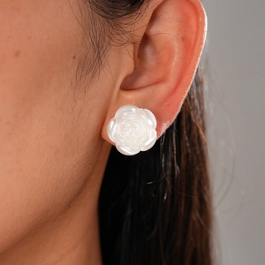 Close-up of white resin rose stud earring with pearl luster on a model ear