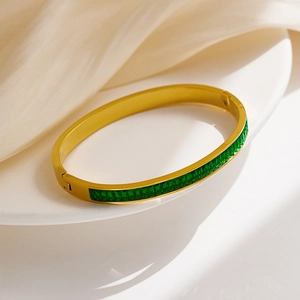 Close-up of gold titanium steel bracelet set with emerald green rectangular stones
