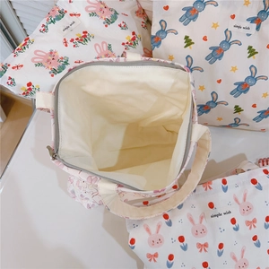 Detail view of cotton tote bags with rabbit prints, zipper closure and inner lining