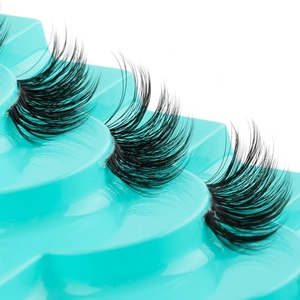 Macro detail of three pairs of dense black synthetic false eyelashes on turquoise stand