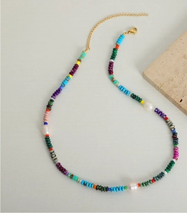 Detail of colorful beaded necklace with white pearls and golden lobster clasp