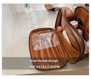 Detail showing the large interior capacity and brush slots of the dark brown makeup bag