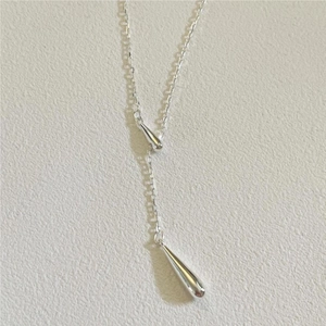 Detailed top view of Y-shaped silver necklace featuring two elegant teardrop pendants