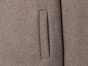 Detailed close-up showing the professional welt pocket stitching on a mocha wool coat