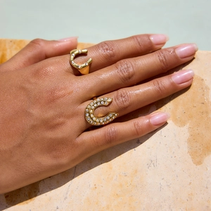 Gold plated horseshoe ring set with sparkling zircon pavé on model with water background