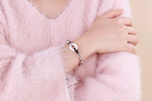 Gros plan du bracelet en résine et acier sur mannequin en pull rose moelleux