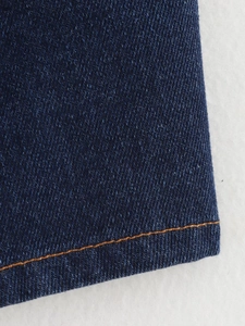Gros plan détaillé du tissu denim bleu foncé avec surpiqûres orange contrastées
