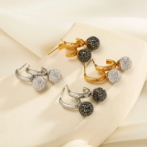 Close-up of pavé crystal ball earrings in gold and silver finish on a display