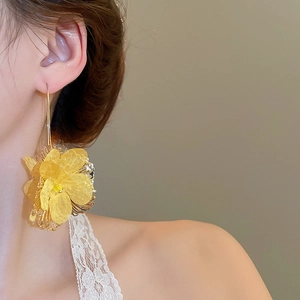 Gros plan sur des boucles d'oreilles fleur 3D jaune avec longs crochets dorés
