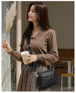 Close-up of black quilted PU leather crossbody bag with wide strap and gold hardware