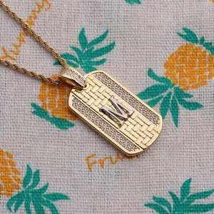 Gros plan du pendentif lettre M rectangulaire doré avec chaîne torsadée et zircons