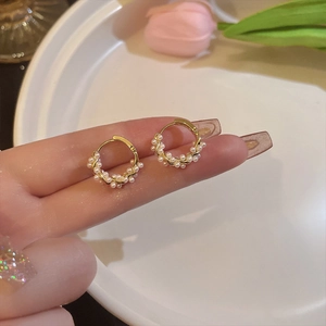 Close-up of elegant gold hoop earrings with small white pearls on a soft background