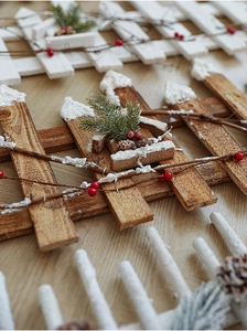 Detailed view of wood Christmas fence with faux pine branches, red berries, and white snow
