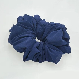 Close-up of deep blue chiffon fabric scrunchie with soft ruffled texture on white background