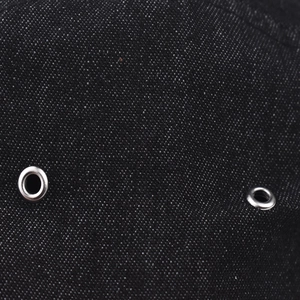 Close-up of silver metal eyelets on vintage black denim fabric of a baseball cap
