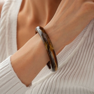 Detail of vintage amber acrylic bangle with tortoiseshell pattern on white knit sleeve