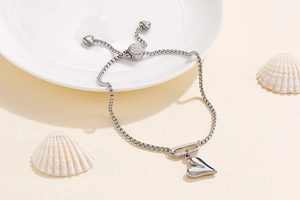 Close-up of silver heart slider bracelet with adjustable chain on a ceramic plate