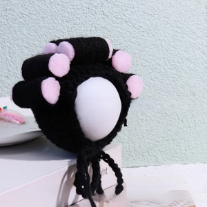 Close-up of handmade black crochet pet wig with pink foam hair rollers on a pedestal