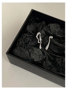 Detail view of irregular molten silver earrings presented in a luxury black gift box