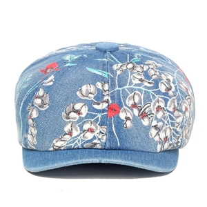 Vintage blue denim newsboy cap with white and red floral patterns on a white background
