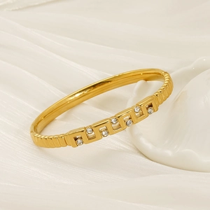 Close-up of gold-plated bangle with hollow geometric patterns and sparkling zircon stones