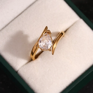 Macro detail of a 18K gold plated wing-shaped ring with a teardrop zircon in a velvet box