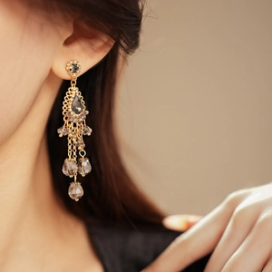 Detailed close-up of vintage gold water drop tassel earrings with champagne crystals