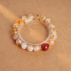 Détail d'un bracelet en perles de cristal jaune avec agate rouge et inserts dorés