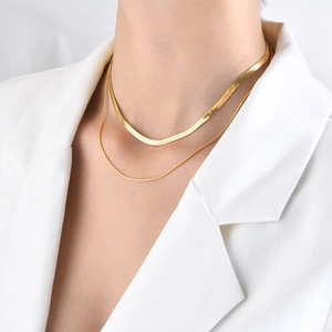 Double-layered 18k gold snake bone chain necklace worn on a model with white blazer