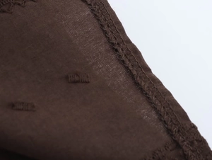Close-up of dark brown fabric showing delicate dot embroidery and quality stitching