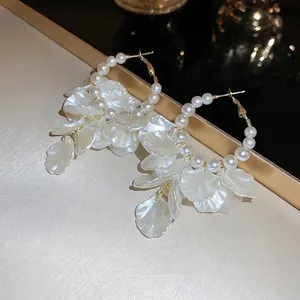Detailed close-up of French vintage gold hoops with white pearls and silk flower tassels