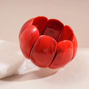 Macro detail of red marble acrylic cuff bracelet with black ink swirl patterns