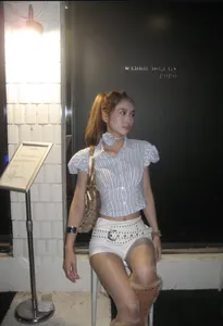Dettaglio di camicia a maniche a sbuffo a righe blu con fiore e cintura borchiata