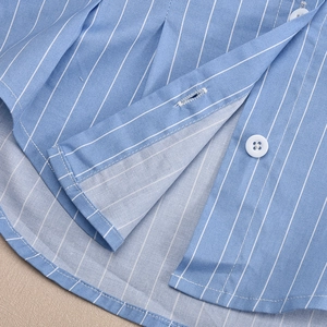 Close-up of white buttons and precise stitching on a blue striped off-shoulder shirt