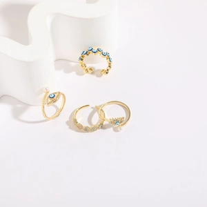 Set of four 14K gold plated evil eye rings with zircons and pearls on white pedestals