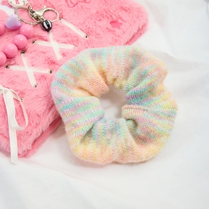 Dettaglio dell'elastico per capelli in maglia sfumata arcobaleno su sfondo rosa estetico