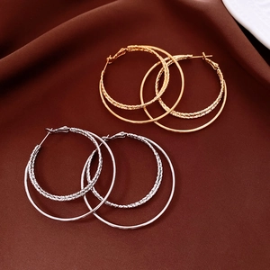 Vue détaillée des boucles d'oreilles créoles dorées et argentées au design torsadé entrelacé