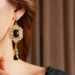Macro detail of vintage water-drop earrings with black gemstones and golden filigree