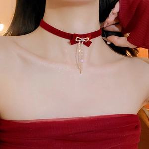 Detail of red velvet choker with rhinestone bow and dangling tassel chain fringe