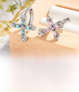 Macro shot of silver-plated cross hoop earrings with pink and blue cubic zirconia stones