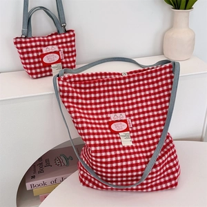 Detail of red and white checkered tote bag set with blue denim straps and text label