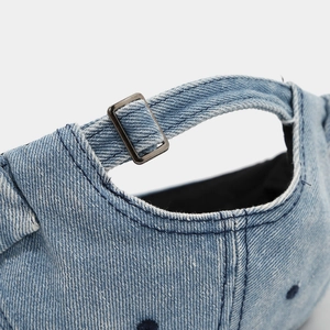 Detail of adjustable metal buckle and washed denim texture on the back of the docker cap
